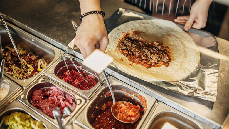Employee putting together a burrito in a fast casual restaurant