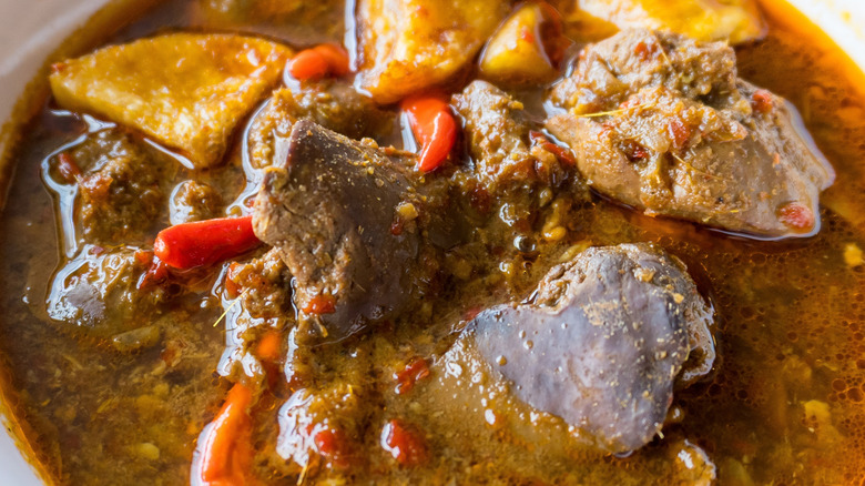 Closeup of meat stew with various bits of offal floating in the broth.