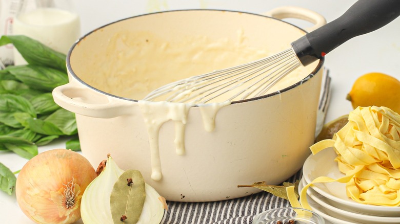 large pot of white sauce and whisk