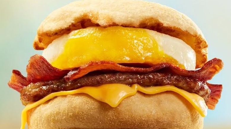 Close-up of a Sausage McMuffin with slices of bacon in between the egg and sausage