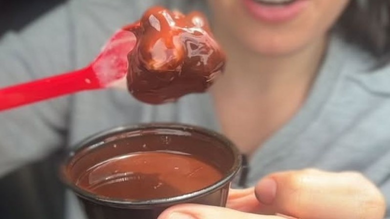 Image of ice cream being dipped in hard shell coating with DQ spoon