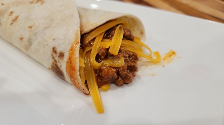 Taco Bell Chili Cheese Burrito on white plate with cheese extended