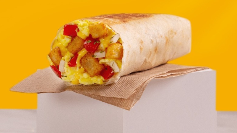 Taco Bell Fiesta Potato Grilled Breakfast Burrito perched on napkin