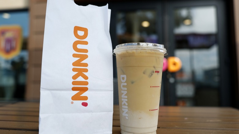 A Dunkin' iced coffee next to a paper bag