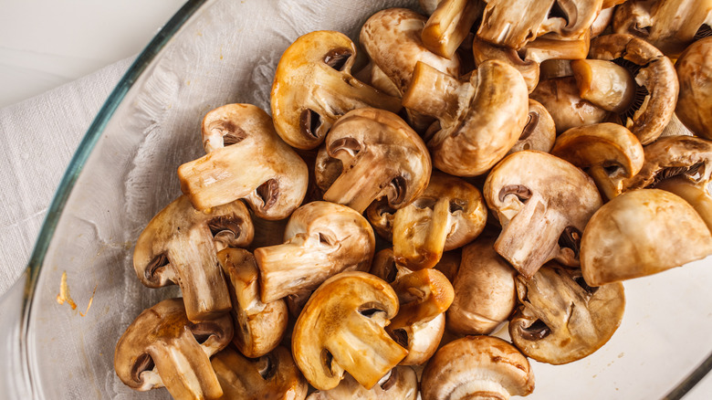 A glass dish holding diced roasted mushrooms on a white background