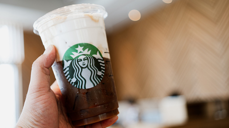 A half-filled Starbucks cold brew coffee with white cold foam.