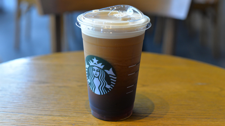 Close up of a Starbucks cold brew in a cup placed on a brown table.