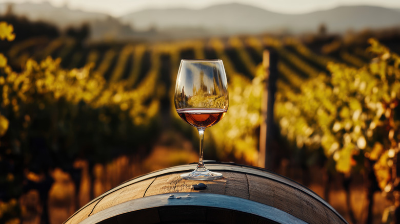 Glass of wine on wine barrel overlooking vineyard