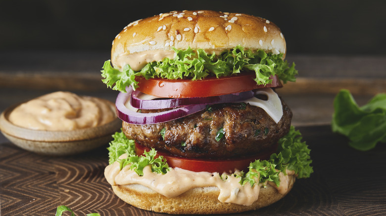 Burger with toppings and a bowl of special sauce