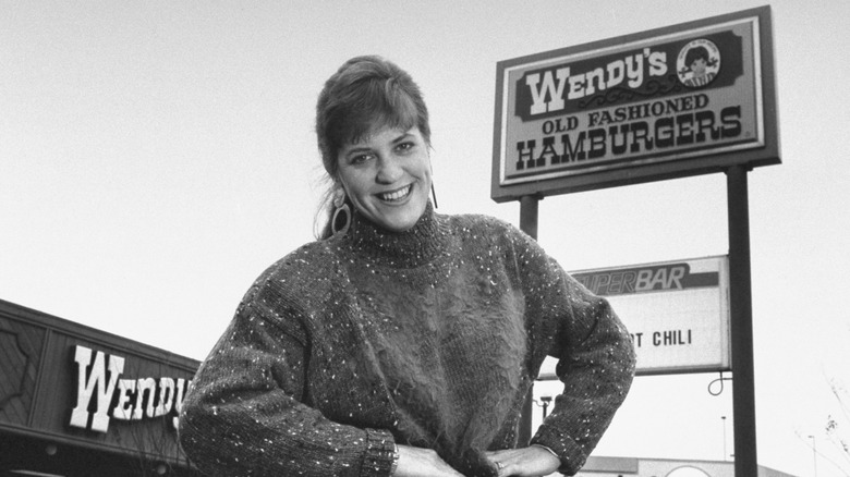 An old photograph of Wendy Morse, Dave Thomas' daughter, in front of a Wendy's restaurant