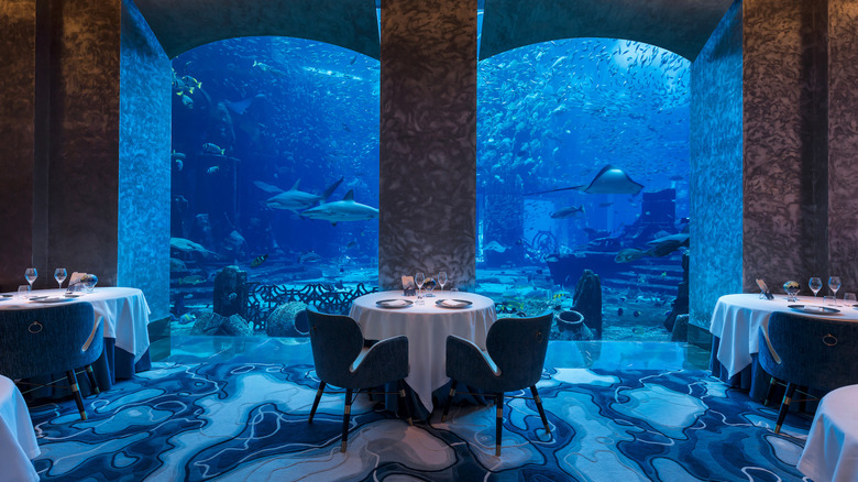Tables next to aquarium with sharks at Ossiano in Dubai