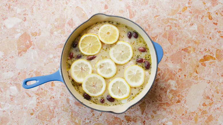 Dutch oven with chicken soup, orzo, olives, fish and lemon slices