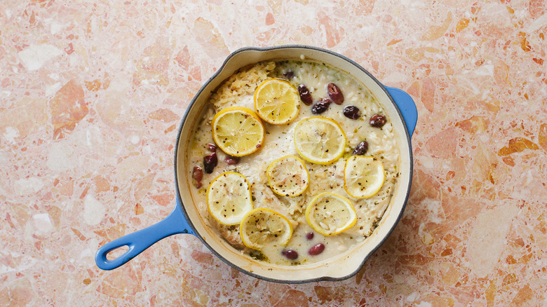 Dutch oven with baked orzo, olives, fish and lemon slices