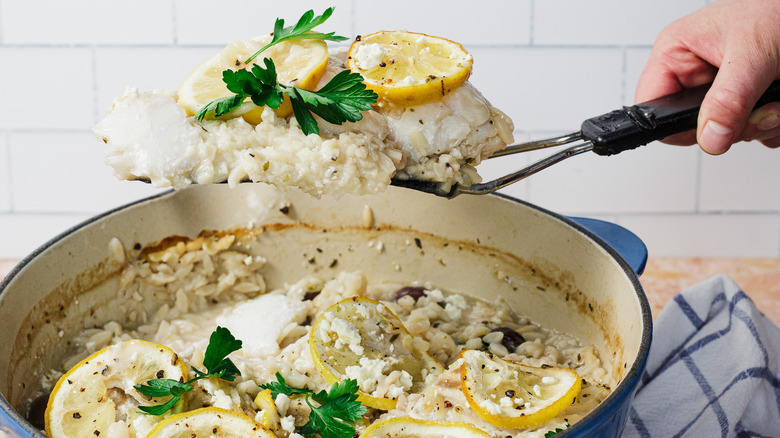 Hand raising spatula with fish out of pot