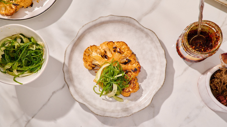 cauliflower steak on a plate with scallion salad