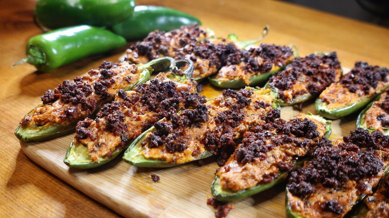 three-ingredient jalapeño poppers laid out on a cutting board beside fresh jalapeño peppers