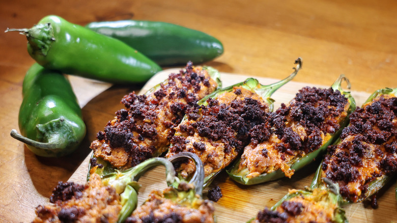 three-ingredient jalapeño poppers on a cutting board next to jalapeño peppers