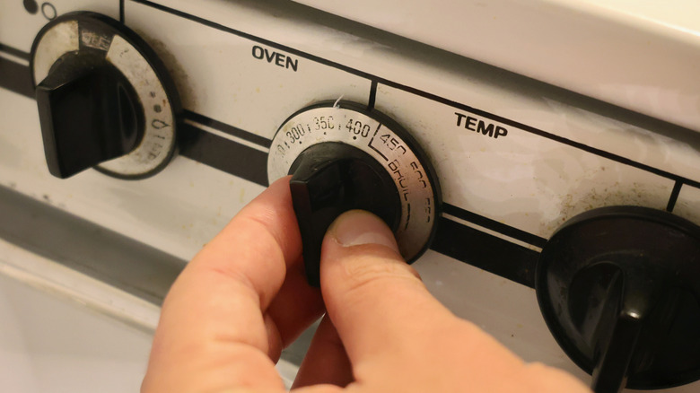 fingers turning oven temperature dial to 400 F