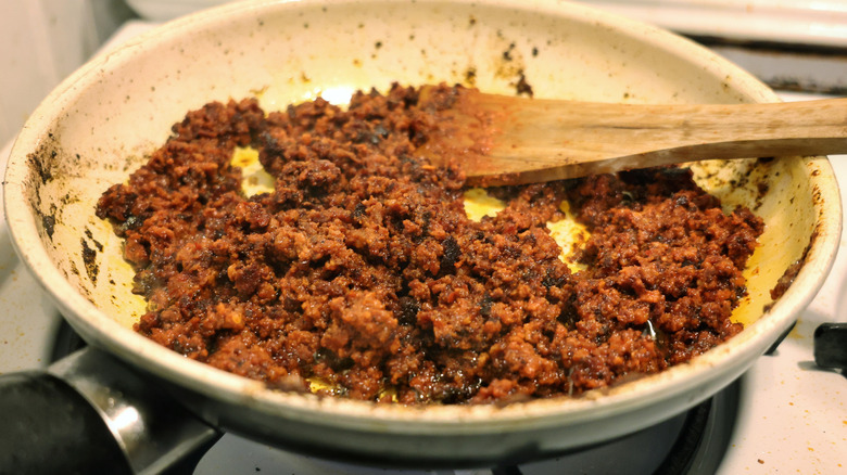 small skillet of cooked chorizo with wooden spatula in it