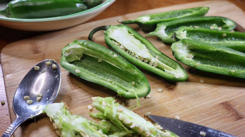 halved jalapeños on a cutting board with a spoon