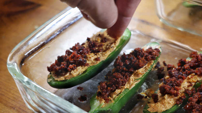 hand sprinkling chorizo onto jalapeño poppers
