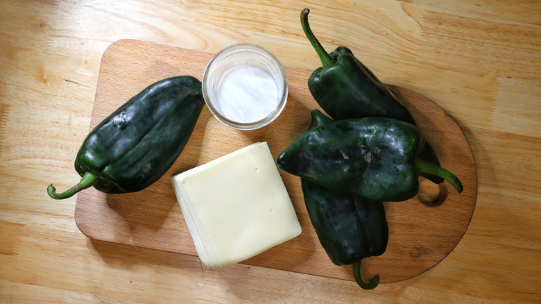 American cheese, milk, and poblano peppers on a cutting board on a wooden table