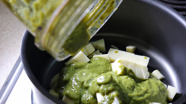 pouring poblano puree into pot with American cheese cubes