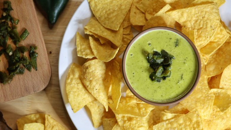 overhead picture of dish of poblano queso garnished with diced roasted poblanos on plate with tortilla chips