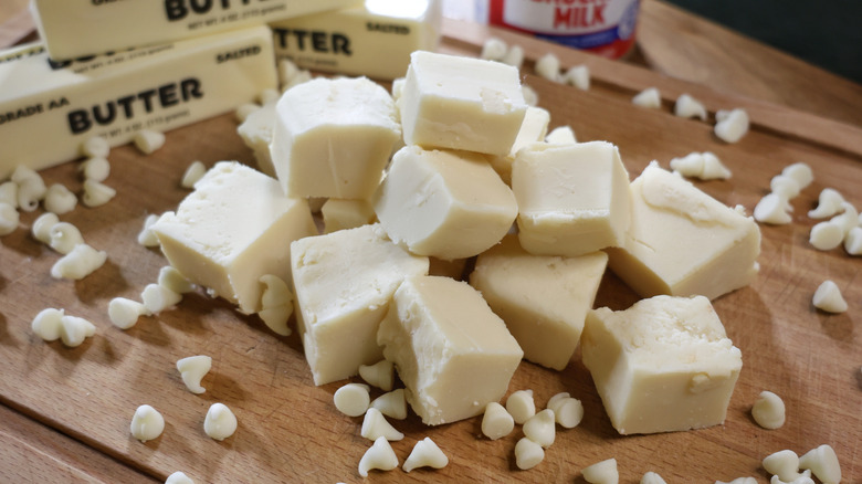 a stack of white chocolate fudge pieces on a wooden cutting board