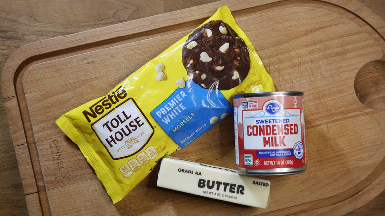 white chocolate chips, condensed milk, and butter on a cutting board