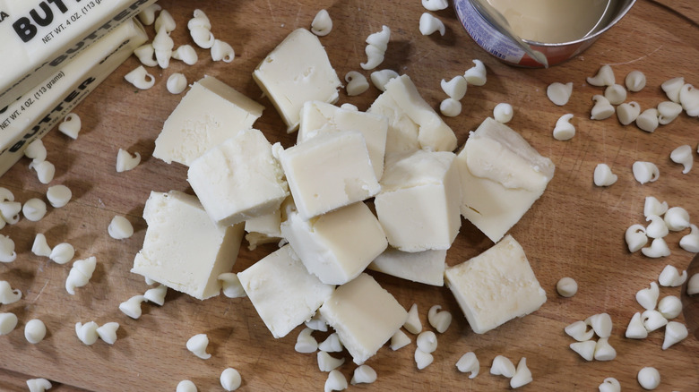 overhead photo of a pile of white chocolate fudge pieecs on a wooden cutting board