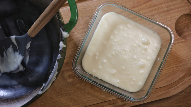 glass dish of white chocolate fudge on cutting board next to pot with spoon