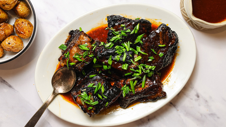 Short ribs garnished with scallions on plate
