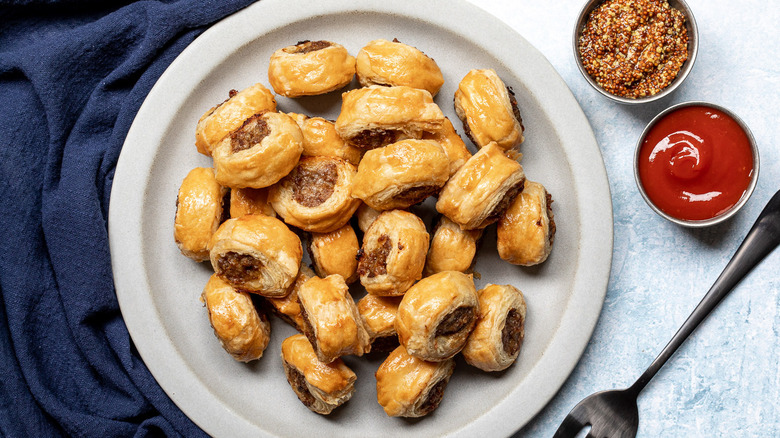 Sausage rolls on plate next to sauces