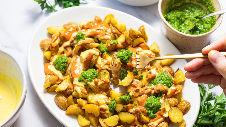 Lifting a fork with potatoes and all sauces over a platter.