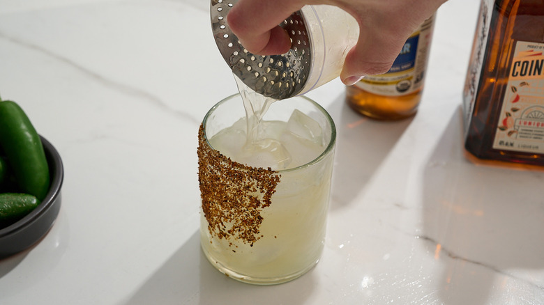 straining cocktail into glass