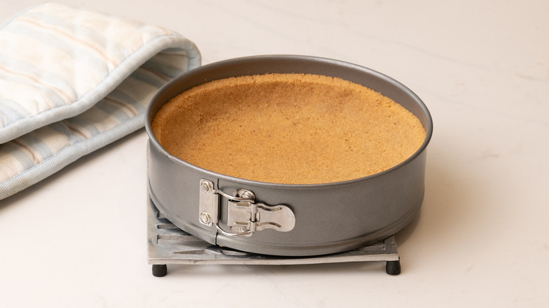 baked graham cracker pie crust in cake pan resting on trivet