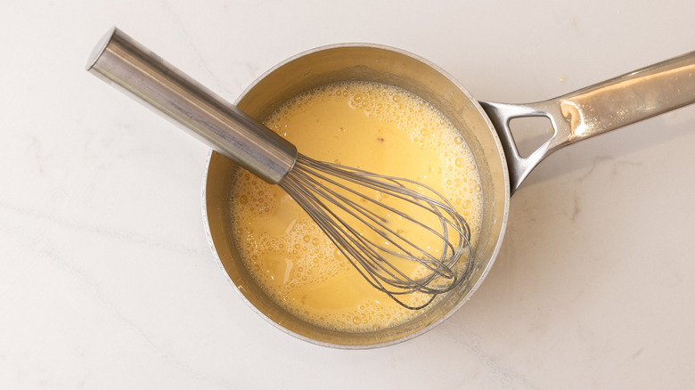 aerial view of elderflower custard base in saucepan with whisk in it