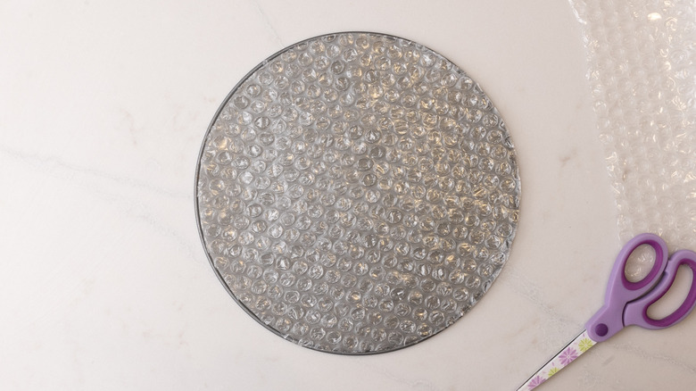 circular bubble wrap on top of cake pan bottom next to scissors