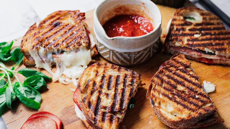 Pizza grilled cheese halves on cutting board with marinara sauce