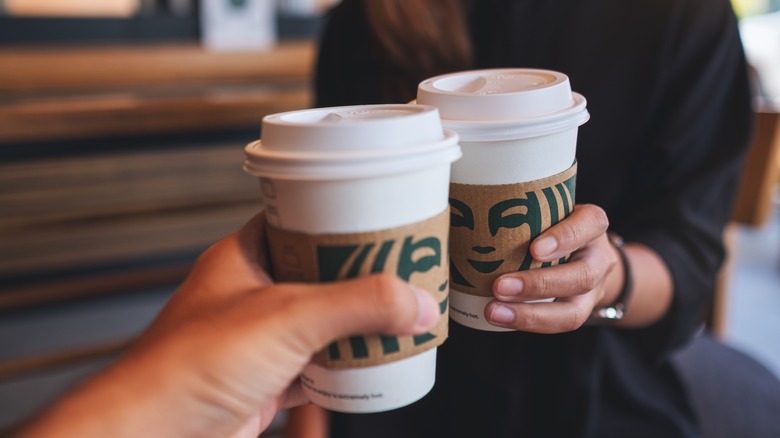 hands cheersing Starbucks cups