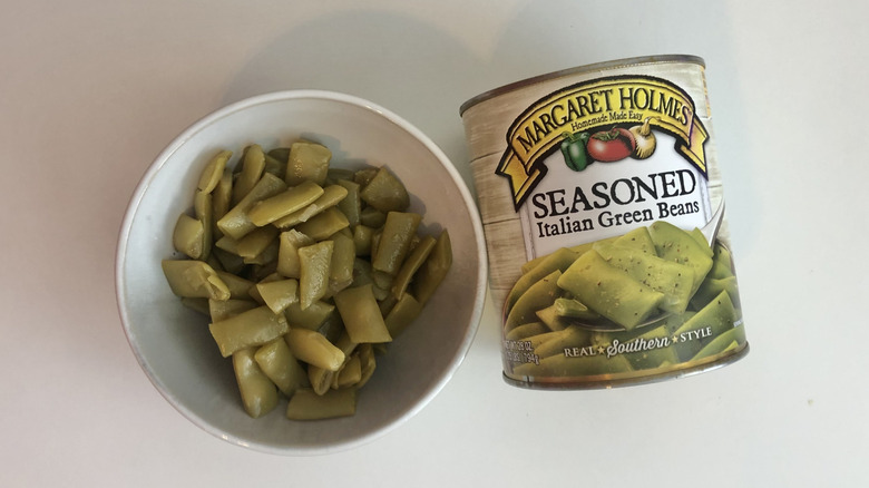 Bowl of canned green beans beside the can that they came from