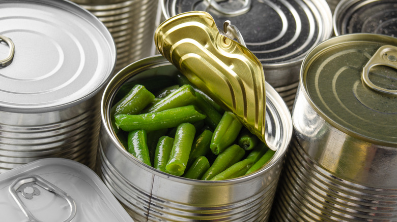 Open can of green beans surrounded by closed cans