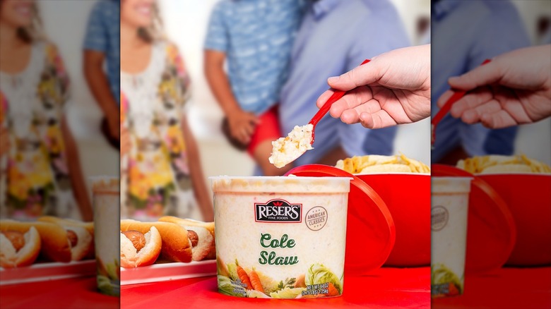 A person lifting a spoonful of Reser's coleslaw out of the tub