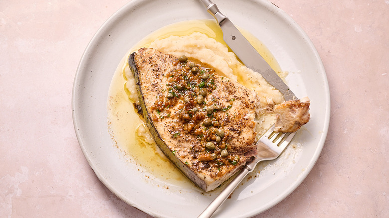 swordfish filet on plate with fork and knife