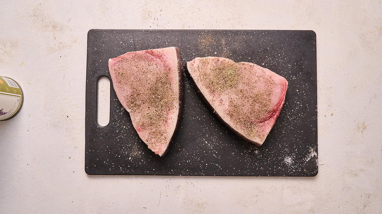 seasoning swordfish steaks on a cutting board