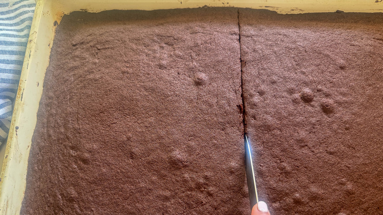 hand slicing cookie sheet in half