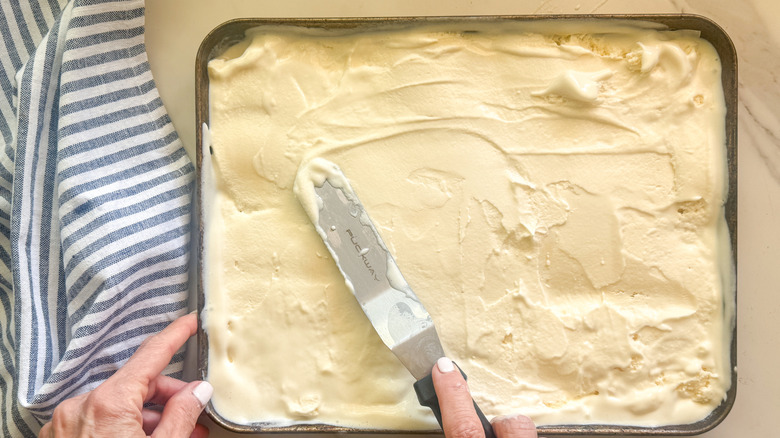 hand spreading ice cream in pan