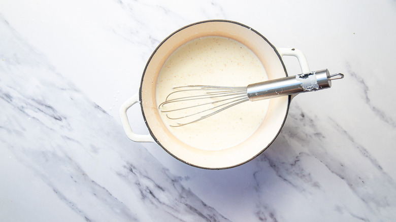 Whisk and creamy white mixture in pot