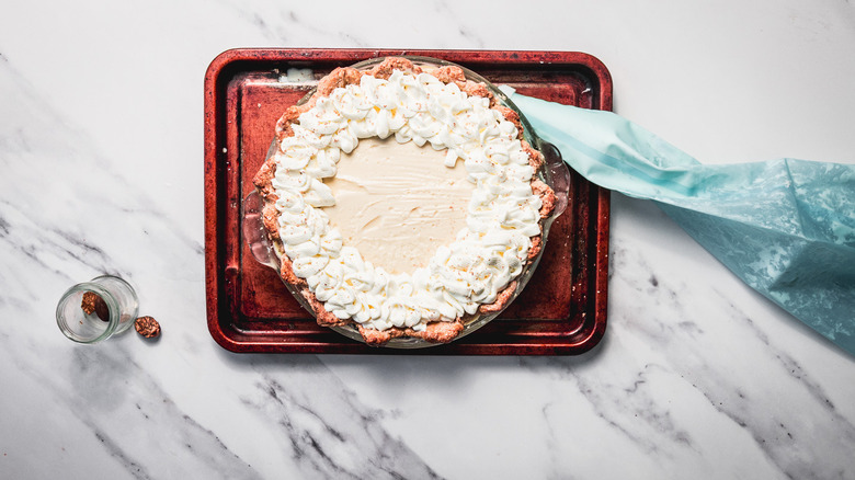 Piping old-fashioned eggnog pie with cream and nutmeg